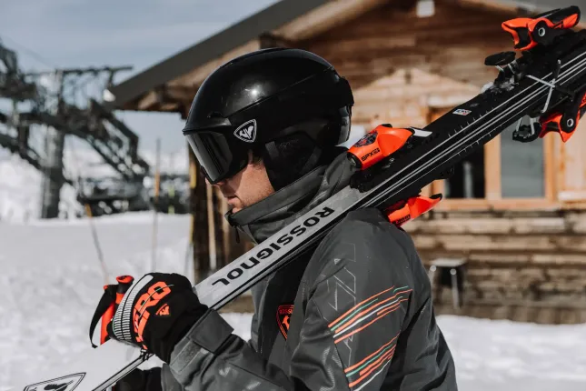 Male Skier holding some skis on their shoulder