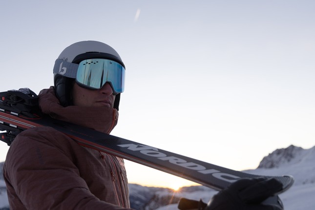 Close up of a male holding a pair of Nordica skis over his shoulder